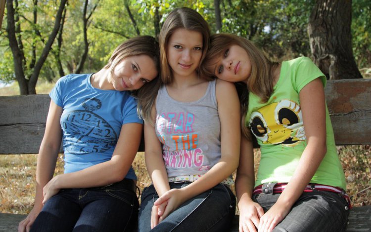 Три молодые подружки в парке на скамейке